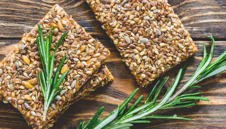 Sesame seed bars with rosemary and sunflower seeds on wooden backgroundの素材