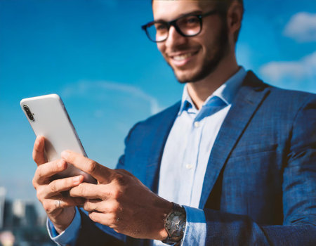 Closeup of a young businessman using a mobile smart phone outdoors.の素材