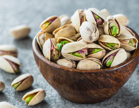 Pistachios nuts in wooden bowl on grey stone background.の素材