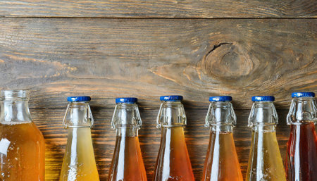 Bottles of tasty drinks on wooden background, top view. Space for textの素材
