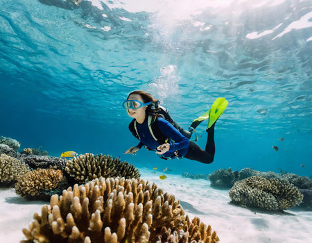 Young woman scuba diver glides over a tropical coral reef.の素材