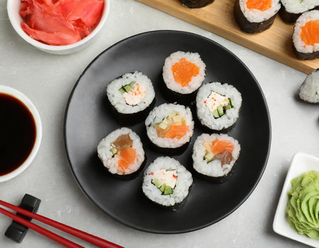 Plate with delicious sushi rolls and chopsticks on table, closeupの素材