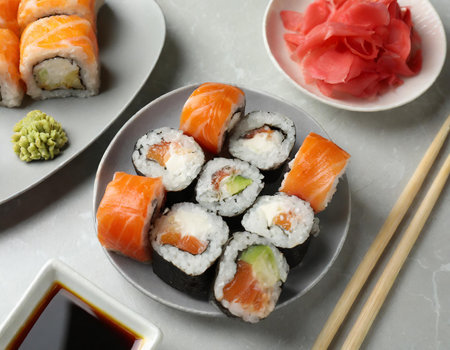 Plate with delicious sushi rolls and chopsticks on white marble tableの素材