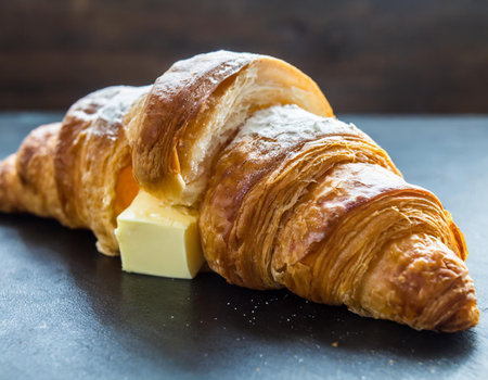 Fresh croissant with butter on black stone background, selective focusの素材