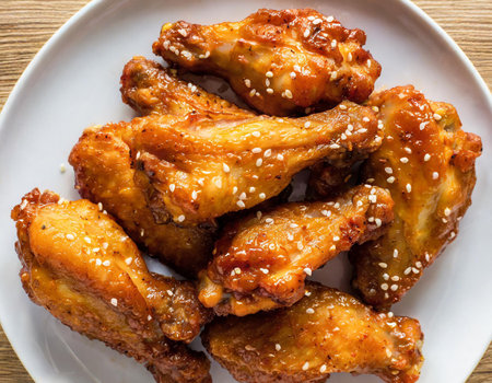 Fried chicken wings with sesame seeds in white plate on wooden tableの素材