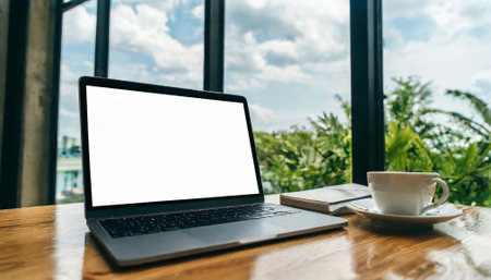 Mockup image of laptop with blank white screen and coffee cup on wooden table in cafeの素材