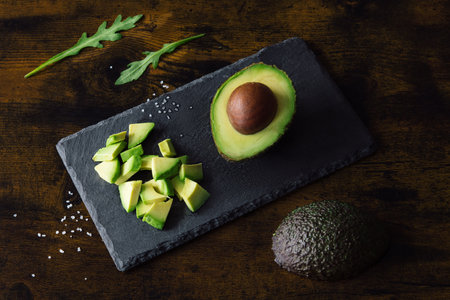 Avocado halves on a wooden cutting Board. Brown background. Top view. Space for textの写真素材