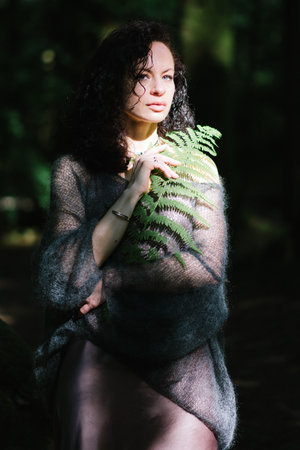 Beautiful young woman sitting on rock near mountain in forestの写真素材