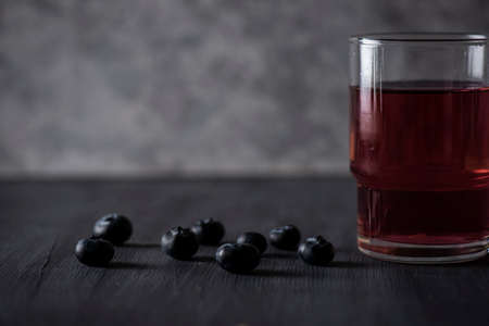 Blueberry Water with some blueberries on the side on a black wooden table and a vintage gray background. Red fruit drinkの写真素材