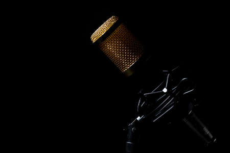 Professional tabletop microphone with cable and mounted on its base with a black background.の写真素材