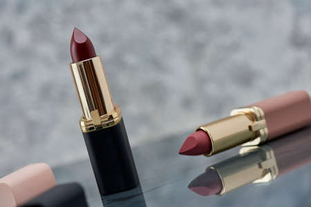 Red lipstick with black and pink on a marble surface with the caps thrown to the side and an elegant compositionの写真素材