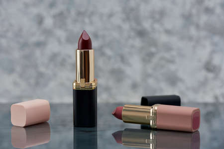 Red lipstick with black and pink on a marble surface with the caps thrown to the side and an elegant compositionの写真素材