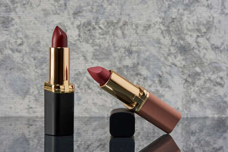 Red lipstick with black and pink on a marble surface with the caps thrown to the side and an elegant compositionの写真素材