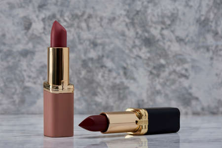 Red lipstick with black and pink on a marble surface with the caps thrown to the side and an elegant compositionの写真素材
