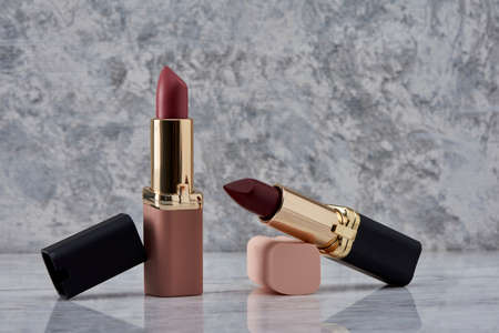 Red lipstick with black and pink on a marble surface with the caps thrown to the side and an elegant compositionの写真素材