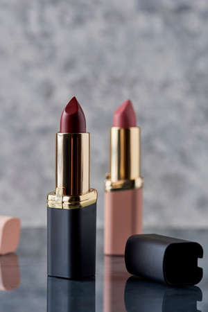 Red lipstick with black and pink on a marble surface with the caps thrown to the side and an elegant compositionの写真素材