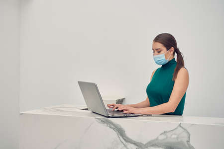 Executive woman checking emails on computer, wearing mask due to the new normal due to the covid-19 pandemicの写真素材