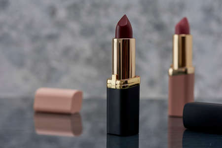 Red lipstick with black and pink on a marble surface with the caps thrown to the side and an elegant compositionの写真素材