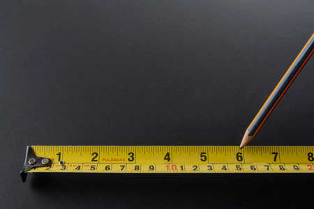 Flexometer or silver color meter with yellow tape measure on a black background