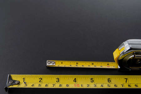 Flexometer or silver color meter with yellow tape measure on a black background