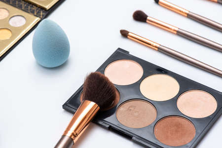 Makeup kit including toners, foundations and eyeshadow palettes on white background