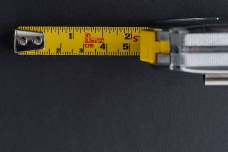 Flexometer or silver color meter with yellow tape measure on a black background