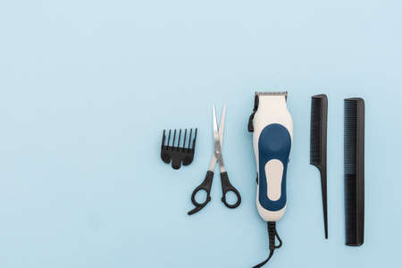 Hair styling and cutting kit such as combs, razor and scissors arranged on a blue background