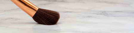Large makeup brush, along with other smaller balls, with a spatula on a marble base