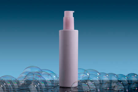 Pink lotion container, with soap bubbles and blue background.