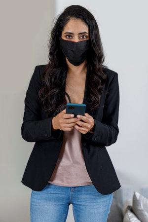 Executive woman with mask using on cell phone working from home. Concept of latin woman with mask for pandemicの写真素材