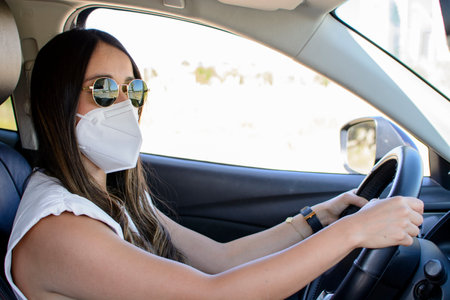 Young latin woman driving a van and wearing mask