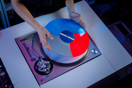 Beautiful Latin girl with headphones changing a vinyl record on the turntable. Dj girl concept in...