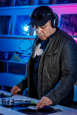 Dj man mixing music on a turntable with vinyl records, and listening on headphones. with vinyl...