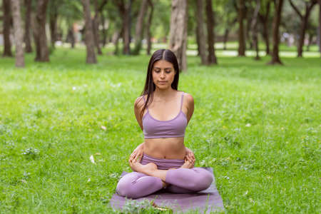 Woman doing yoga poses on green grass in parkの写真素材