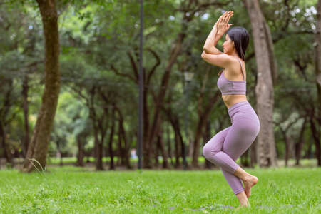 young woman in purple sportswear, doing yoga outdoorsの写真素材