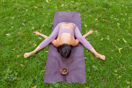 Woman doing yoga poses on green grass in park