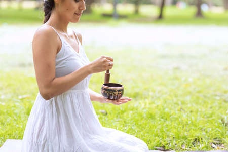 Woman playing a Tibetan bowl in the park while meditatingの写真素材