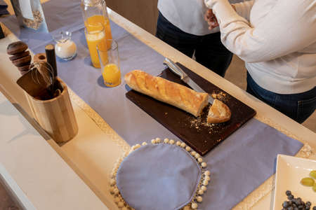 bread cut on a kitchen counter accompanied by juice, milk and granola