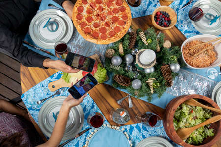 several hands with cellphones taking photos of food at the christmas dinner tableの写真素材