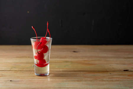 Cherries in a glass for cocktails or alcoholic drinks, on a wooden tableの写真素材