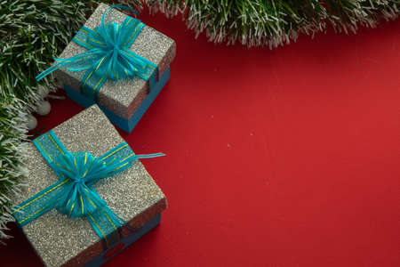Christmas background with gift boxes with blue bow, green branches and red backgroundの写真素材