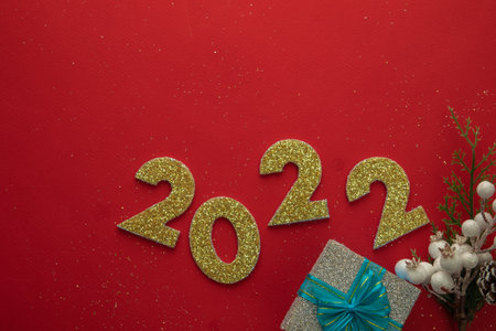 Happy New Year 2022 text with a gift box and red background.