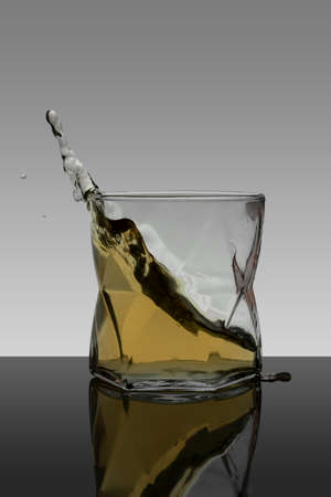 vertical portrait splash of whiskey in crystal glass with gradient backgroundの写真素材