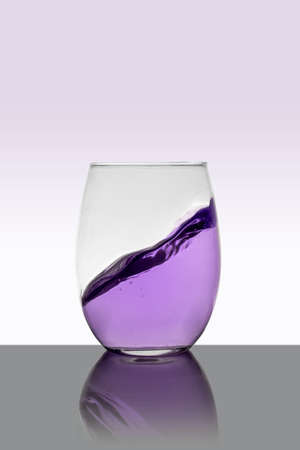 Purple drink in glass with a splash and white backgroundの写真素材