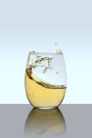 Glass cup with drink in motion with a white backgroundの写真素材