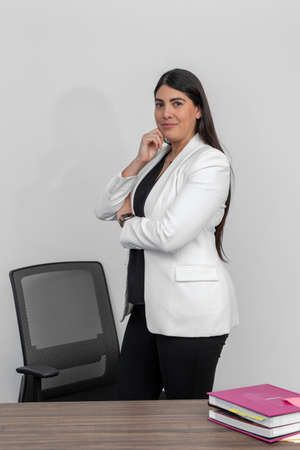 Portrait of confident latin businesswoman and looking at camera, standing with arms crossed smiling.