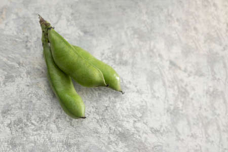 Bouquet of fresh broad beans in shell on a vintage background and space for text