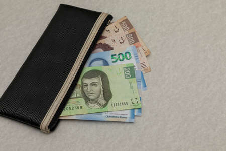 Wallet with Mexican pesos bills of different denominations on a table with copy spaceの写真素材