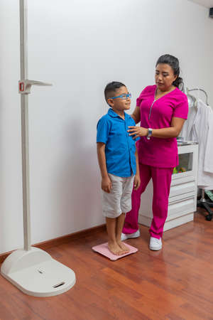 Pediatric doctor weighing a child in her office with a floor scale