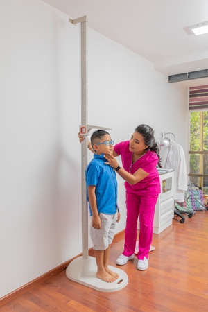 Latina pediatrician measuring a child with a wall ruler in her officeの写真素材